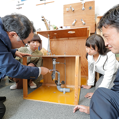 排水トラップの実技を笑顔で見守る講師